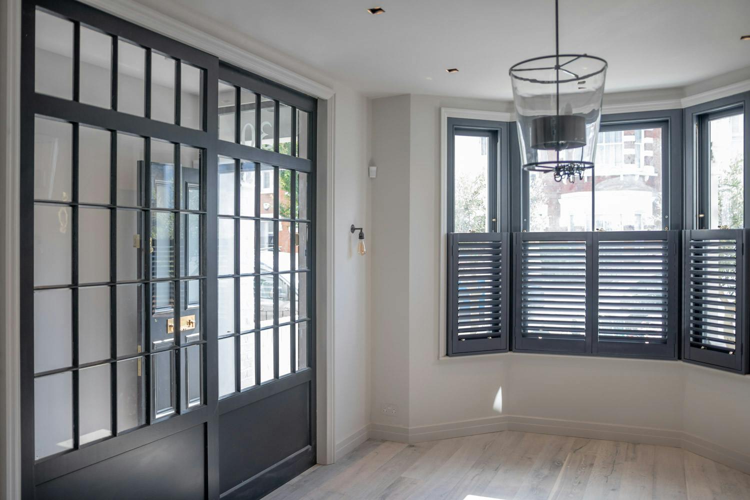 living room with timber bay window with plantation shutters and internal georgian doors and screen