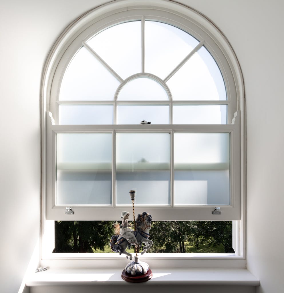 Frosted sash window that's slightly open with bespoke arched shape and design